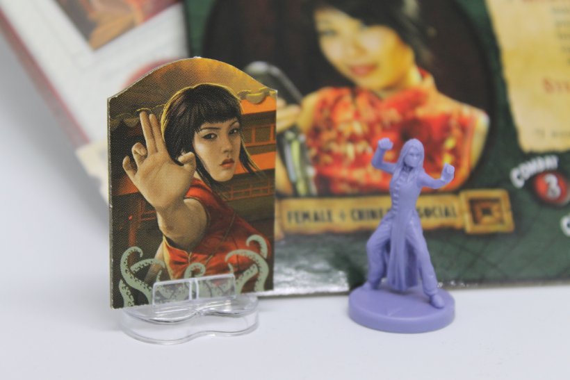 Standee di Eldritch Horror a sinistra e miniatura di Fortune and Glory: the Cliffhanger Game a destra.